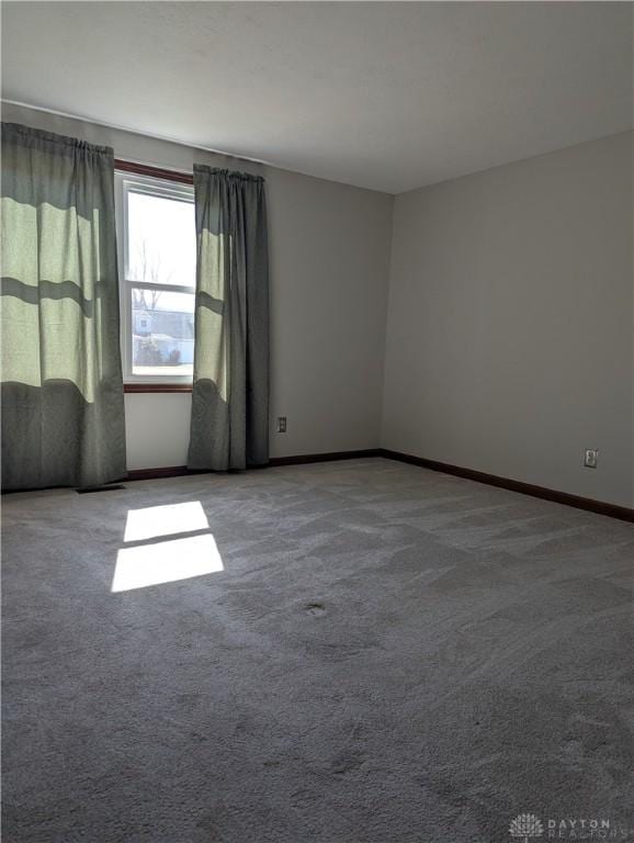 carpeted spare room featuring baseboards