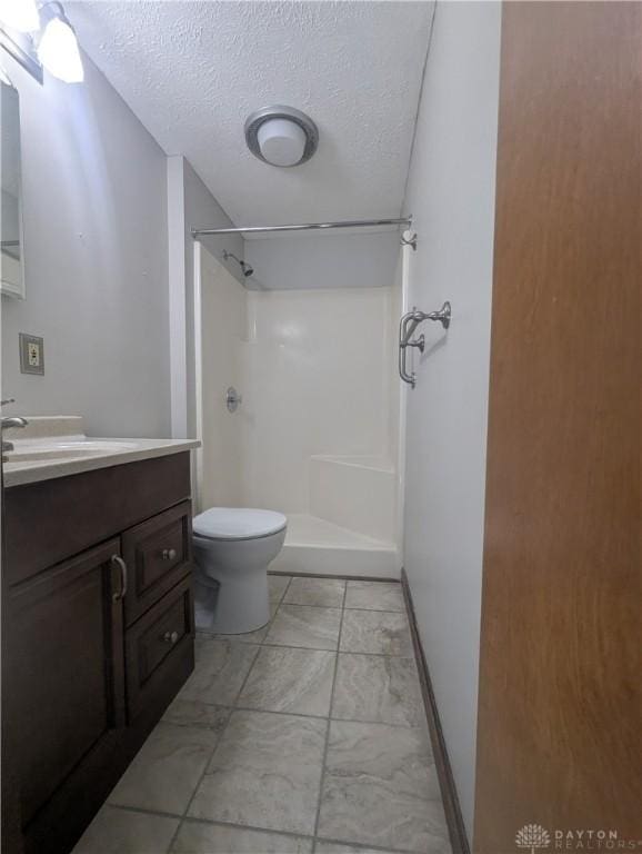 bathroom featuring vanity, walk in shower, a textured ceiling, toilet, and marble finish floor