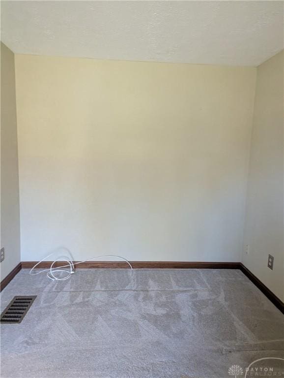 spare room with visible vents, carpet floors, and baseboards