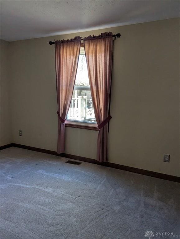 spare room featuring visible vents, light carpet, a textured ceiling, and baseboards