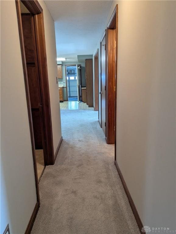 corridor featuring light carpet and baseboards