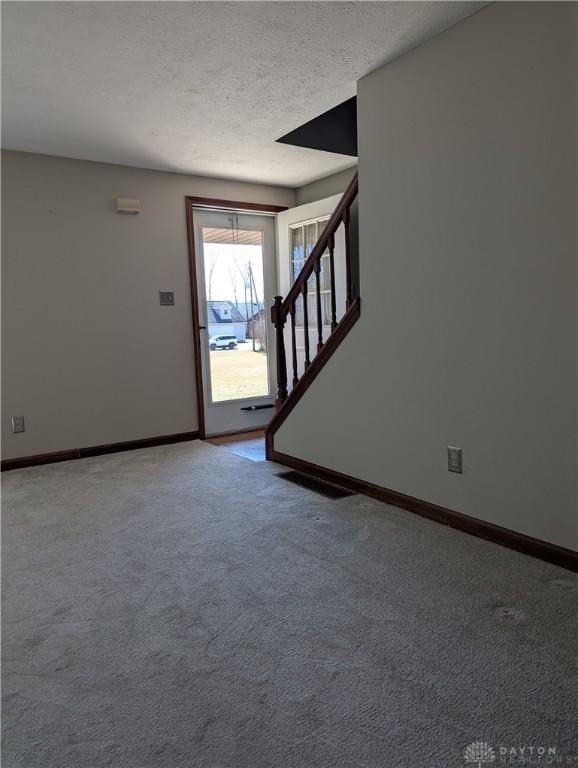 foyer with baseboards, carpet, stairs, and a textured ceiling