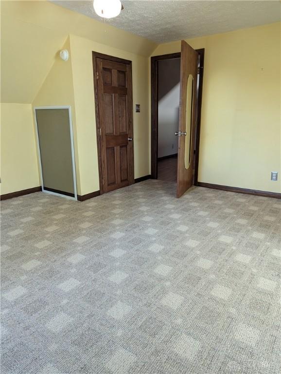 empty room featuring carpet flooring, a textured ceiling, and baseboards