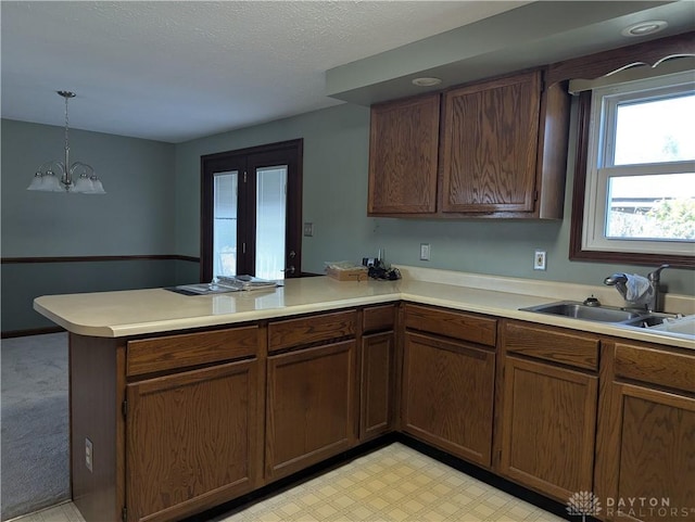 kitchen featuring a sink, a peninsula, pendant lighting, and light countertops