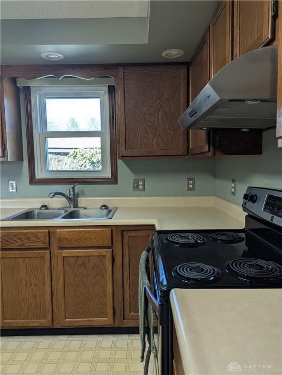 kitchen with stainless steel range with electric stovetop, under cabinet range hood, a sink, light countertops, and light floors