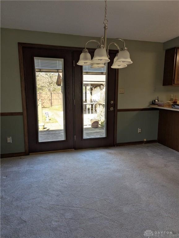 unfurnished dining area with light colored carpet and baseboards