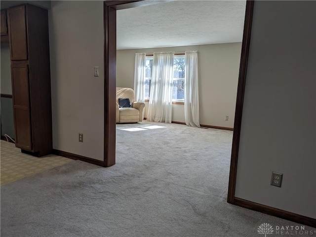 spare room with baseboards, light colored carpet, and a textured ceiling