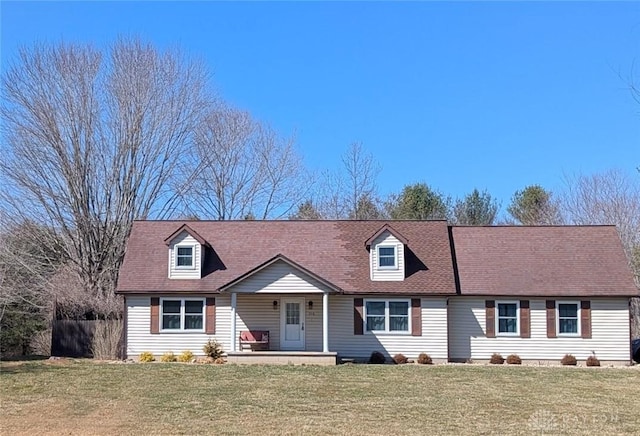 new england style home featuring covered porch, a front lawn, and fence