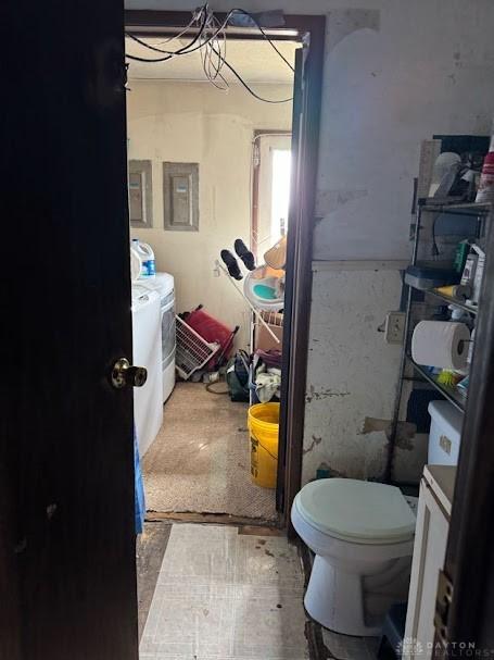 bathroom with electric panel, toilet, and washer and clothes dryer