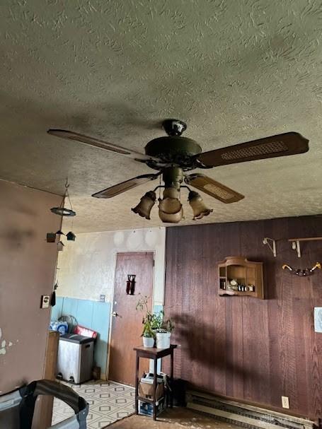 interior space featuring a textured ceiling, a baseboard heating unit, and a ceiling fan