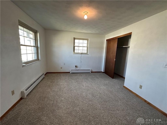 unfurnished bedroom with a closet, baseboard heating, carpet flooring, and baseboards