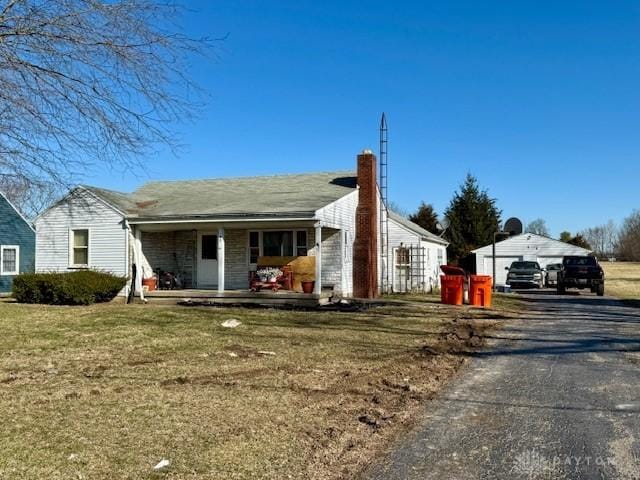 view of front of property featuring a garage, a porch, a chimney, and a front yard