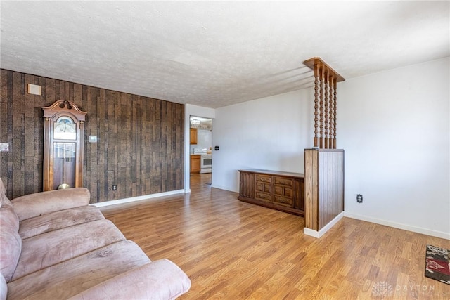 living room featuring baseboards, a textured ceiling, and light wood-style flooring