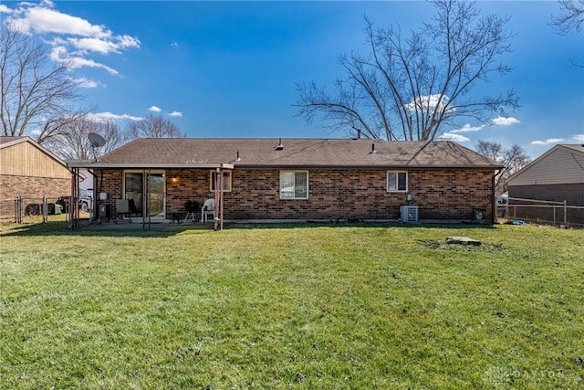 back of house featuring fence, a lawn, and brick siding