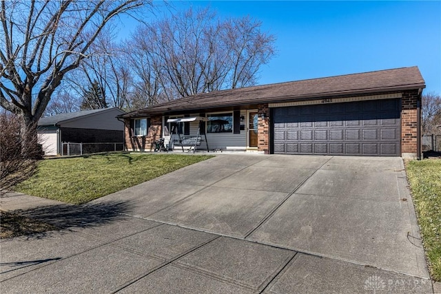 view of front of home featuring brick siding, fence, a front yard, a garage, and driveway