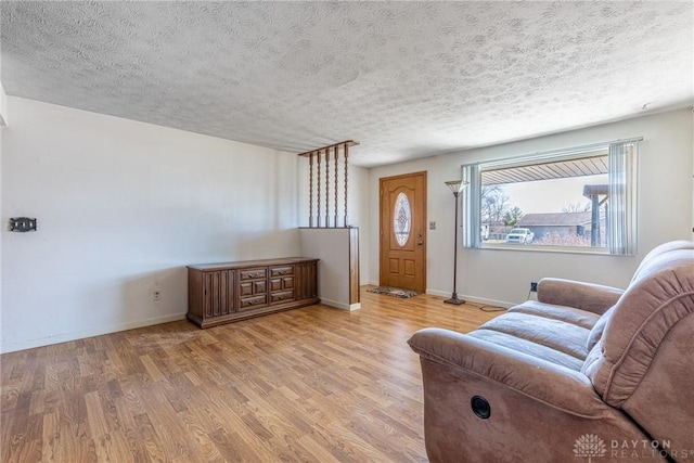 living area featuring wood finished floors, baseboards, and a textured ceiling