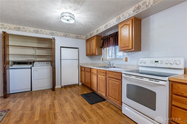 kitchen with white appliances, light countertops, light wood finished floors, and a sink