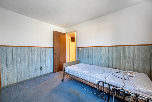 carpeted bedroom with wood walls and wainscoting