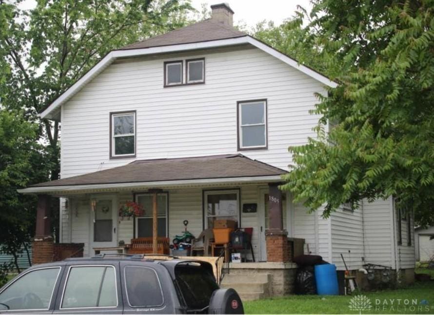 view of front facade featuring a porch and a chimney