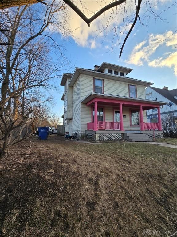 american foursquare style home featuring a porch and a front yard