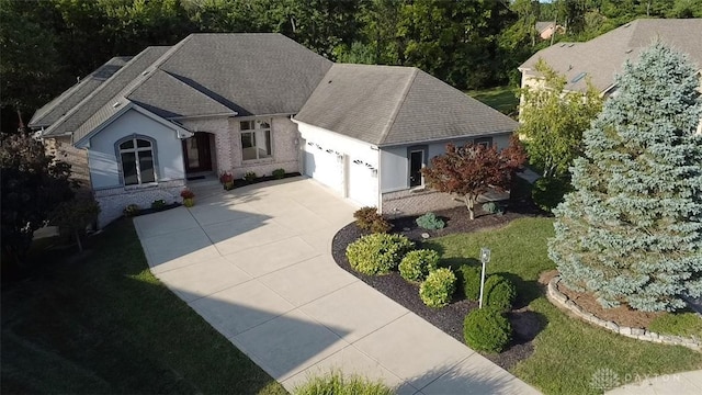 ranch-style house with a front lawn, roof with shingles, concrete driveway, an attached garage, and brick siding