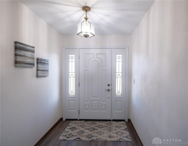 foyer entrance featuring baseboards and dark wood-type flooring