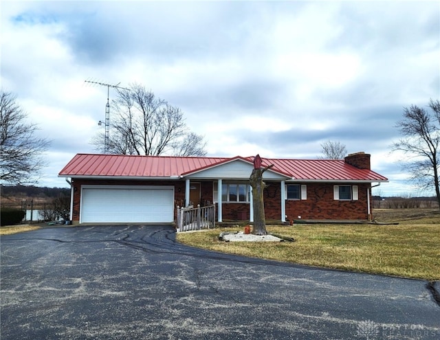 ranch-style house with brick siding, aphalt driveway, a chimney, an attached garage, and a standing seam roof