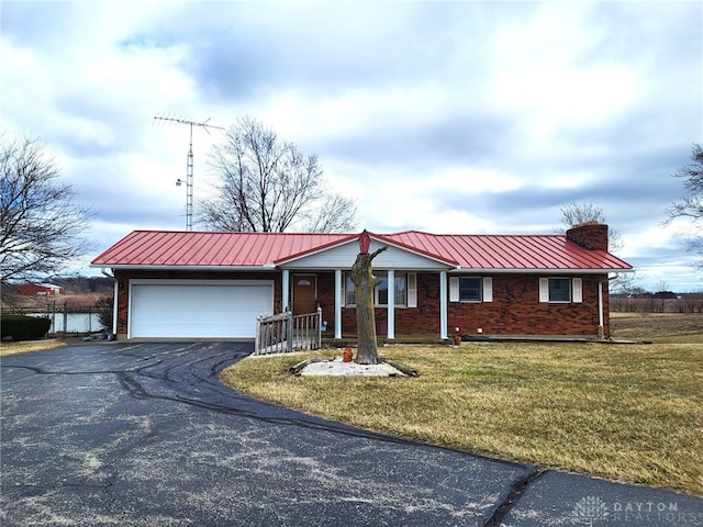 ranch-style home with driveway, a front yard, a garage, brick siding, and a chimney