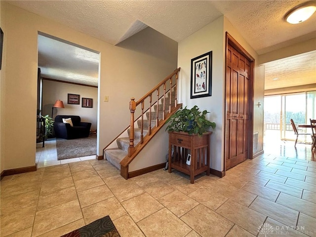 entrance foyer with visible vents, a textured ceiling, stairway, light tile patterned floors, and baseboards