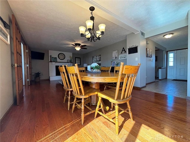 dining room with baseboards, a textured ceiling, wood finished floors, and ceiling fan with notable chandelier