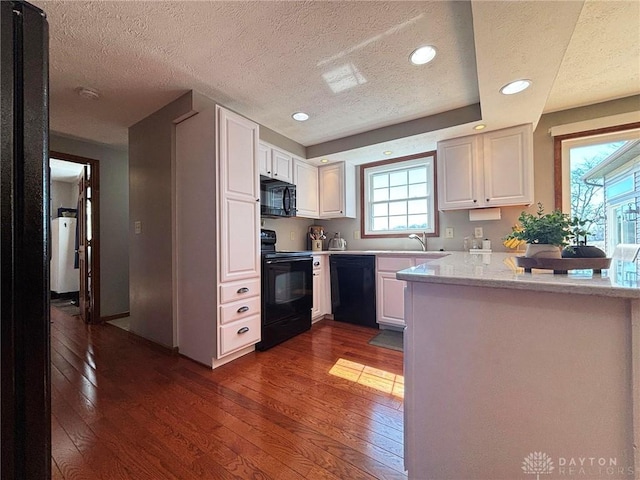 kitchen featuring white cabinetry, black appliances, a peninsula, and dark wood-style flooring