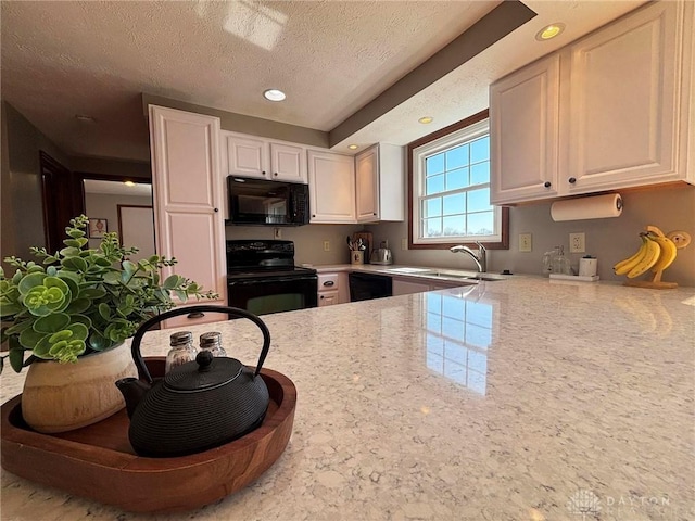 kitchen with recessed lighting, a sink, black appliances, white cabinets, and a textured ceiling