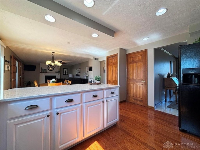 kitchen featuring dark wood-type flooring, a textured ceiling, white cabinetry, black refrigerator with ice dispenser, and hanging light fixtures