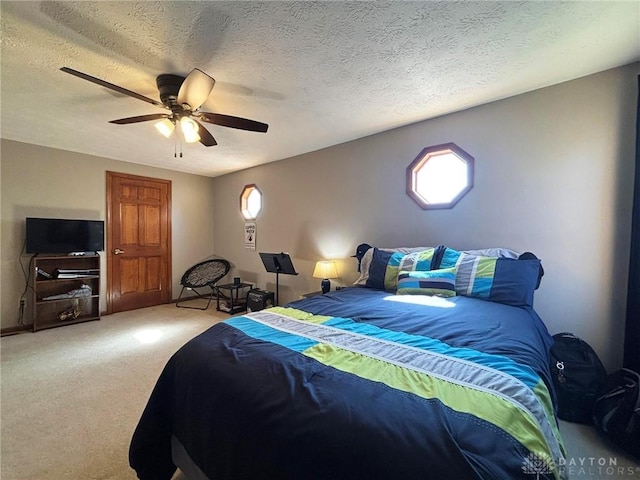 bedroom featuring multiple windows, carpet floors, a textured ceiling, and ceiling fan