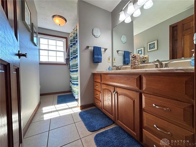 bathroom with tile patterned floors, baseboards, a textured ceiling, and double vanity