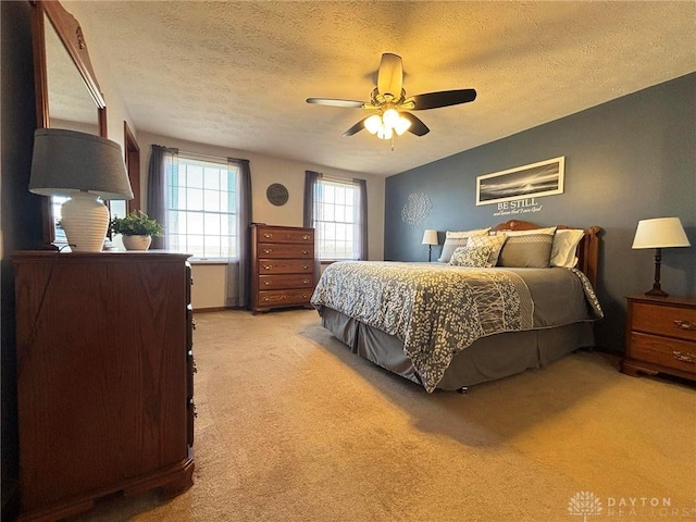 bedroom with light colored carpet, ceiling fan, and a textured ceiling