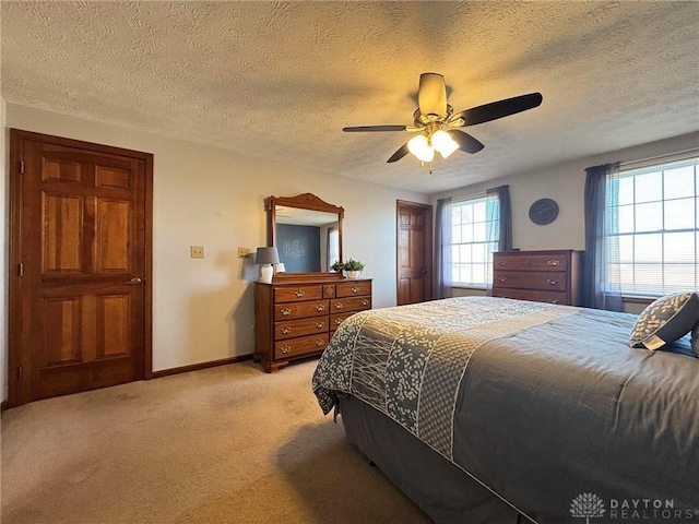 bedroom with ceiling fan, a textured ceiling, baseboards, and light carpet