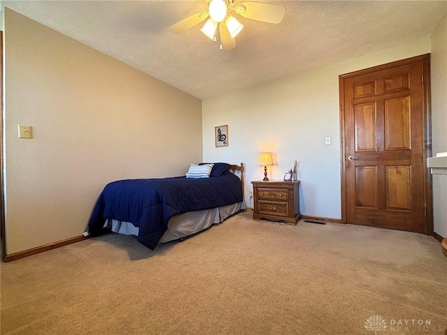 bedroom featuring baseboards, light colored carpet, ceiling fan, and a textured ceiling