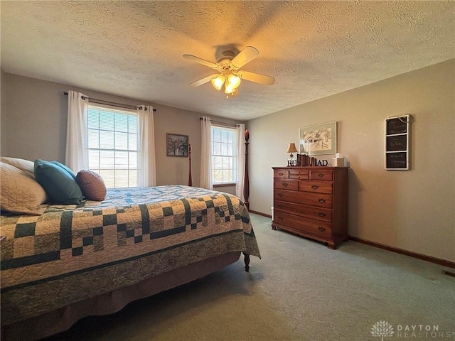 bedroom featuring visible vents, a ceiling fan, a textured ceiling, baseboards, and light colored carpet