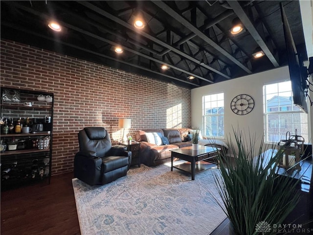 living room with beamed ceiling, brick wall, and wood finished floors