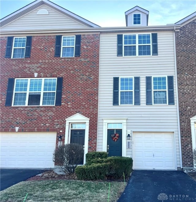 townhome / multi-family property featuring brick siding, driveway, and a garage