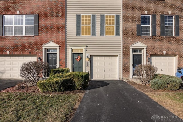 view of front of home with aphalt driveway, an attached garage, and brick siding