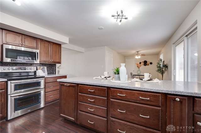 kitchen with dark wood finished floors, backsplash, appliances with stainless steel finishes, and ceiling fan