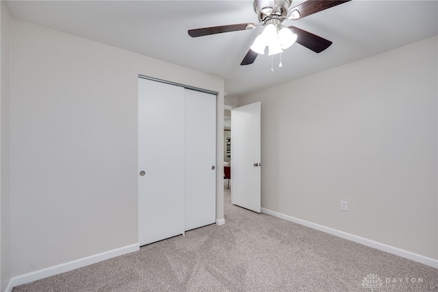 unfurnished bedroom with baseboards, light carpet, a closet, and a ceiling fan