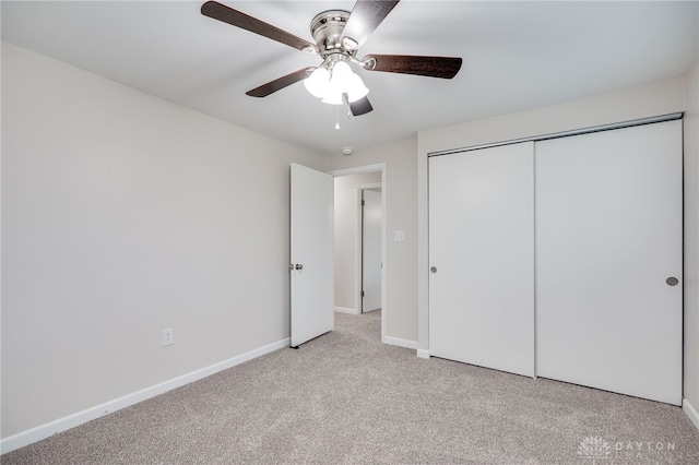 unfurnished bedroom featuring baseboards, light carpet, a closet, and a ceiling fan