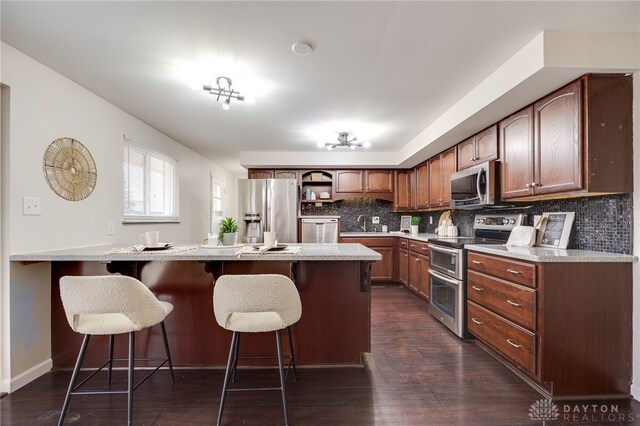 kitchen with a breakfast bar, tasteful backsplash, stainless steel appliances, a peninsula, and light countertops