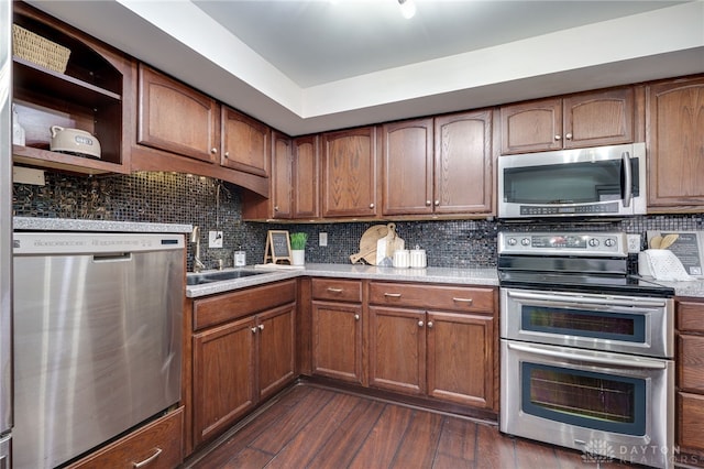 kitchen featuring backsplash, dark wood finished floors, appliances with stainless steel finishes, brown cabinetry, and light countertops