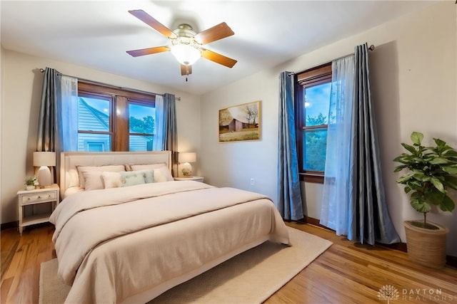 bedroom with a ceiling fan, multiple windows, and wood finished floors