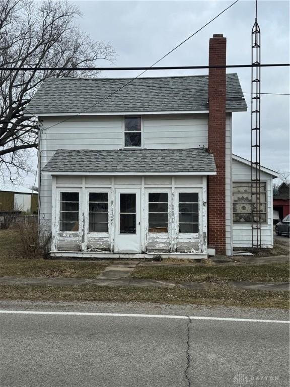 view of front of house with roof with shingles and a chimney