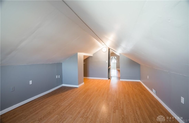 additional living space with baseboards, lofted ceiling, and wood finished floors